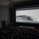 Vollbesetzter Kinosaal mit Surfermovie auf der Leinwand.